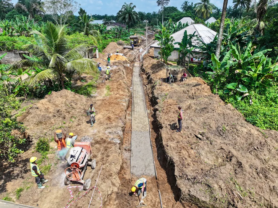 Aerial view of a long drainage excavation with crews working along the trench