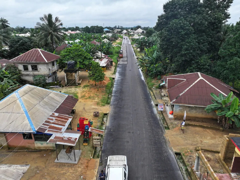Aerial view along a finished roadway bordered by houses and vegetation